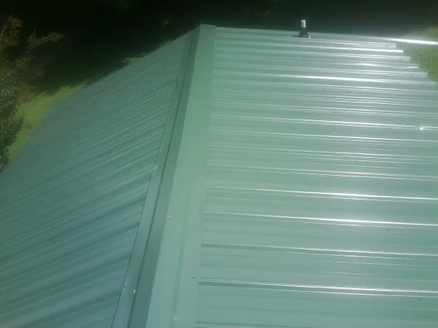 New green metal panels meeting at the ridge of a roof — Flat Roof Repair work by our crew in Brea