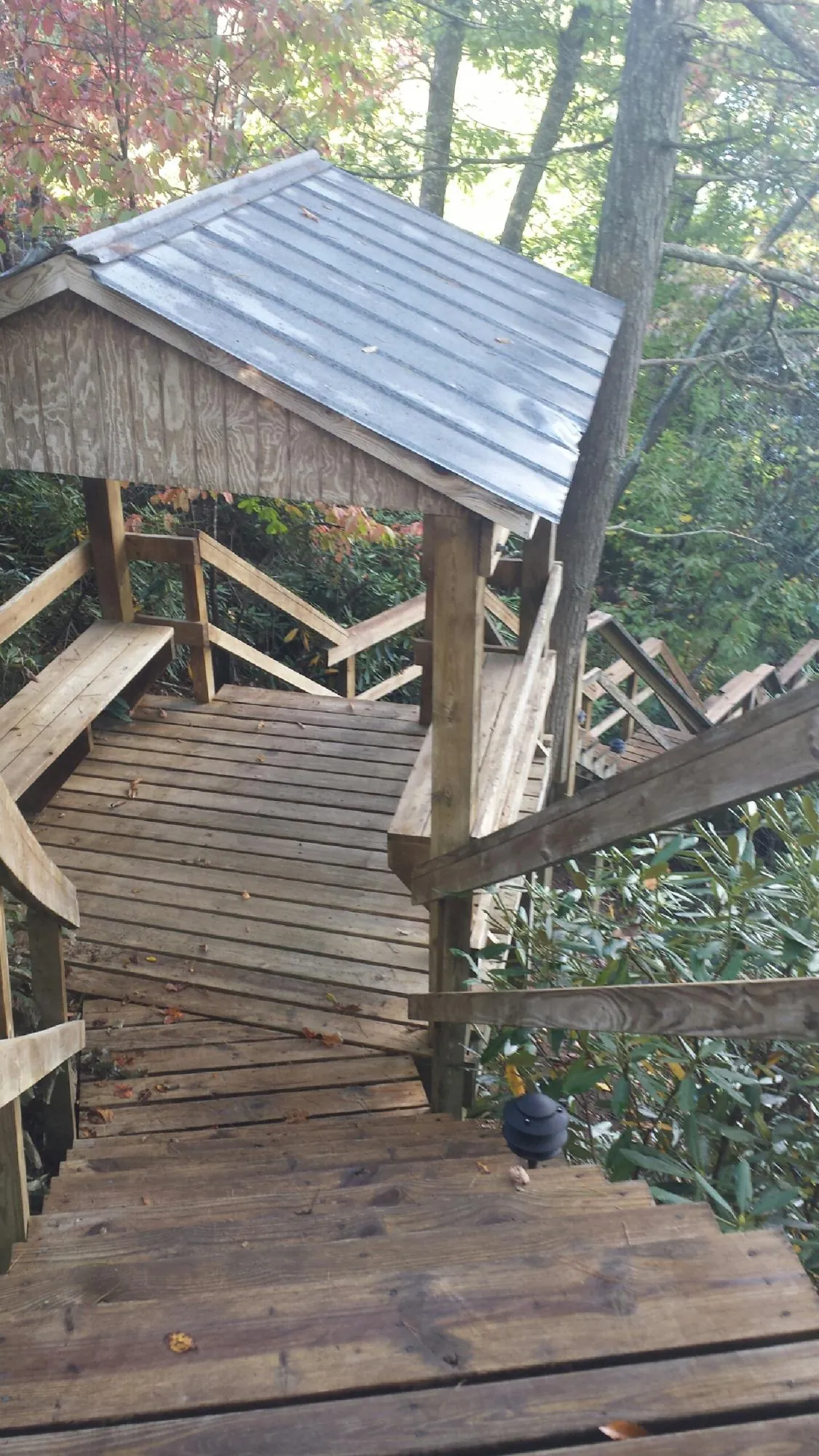 Metal roofed shelter over wooden steps on a wooded walkway — Skylight Repair & Installation work by our crew in Brea