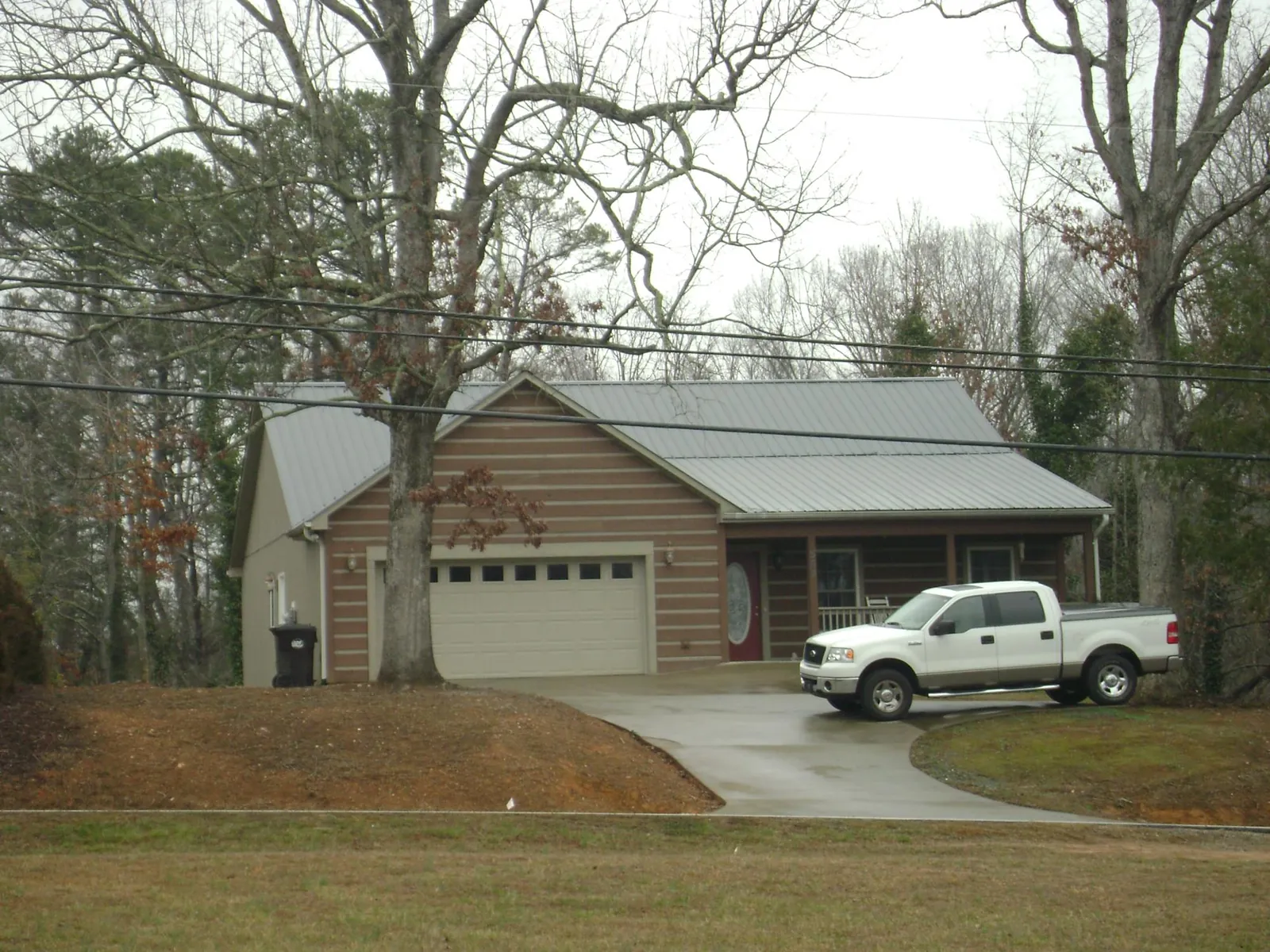 Gray metal roof on a log sided house with an attached two car garage in Brea