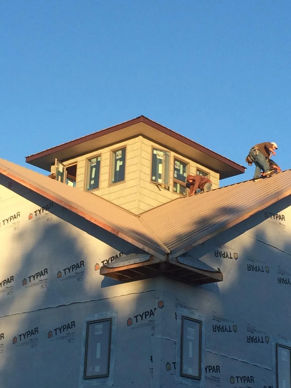 Roofers working around a rooftop cupola on a new metal roof at sunset — Roof Waterproofing in Brea by Roofing Brothers